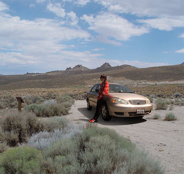 Jenny Odell leaning against her car. Both she and the car have been photoshopped into a desert area.