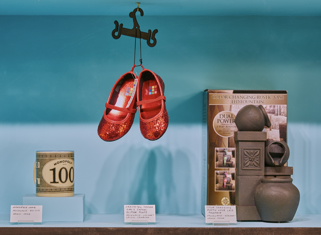 a closeup of the leftmost display, showing a Monopoly mug, red sparkly children's shoes, and an LED fountain