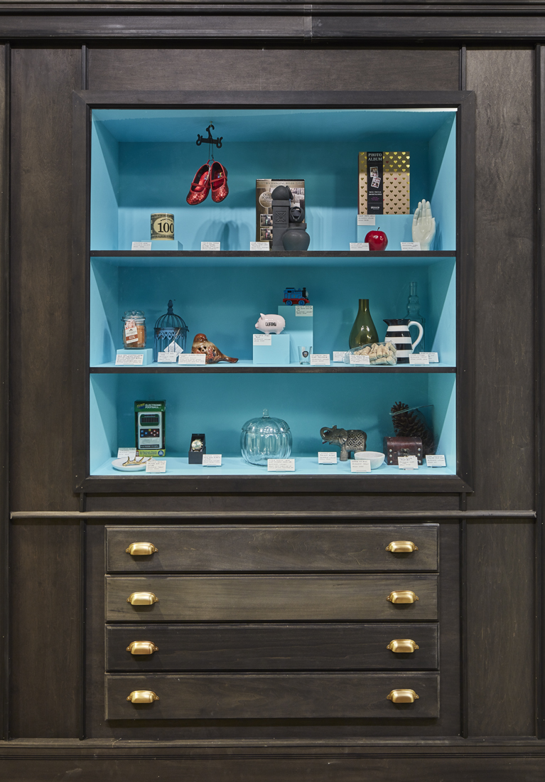the leftmost display section, showing objects from Walmart, including a small piggy bank, a black and white striped mug, and a clear glass pumpkin-shaped candy jar