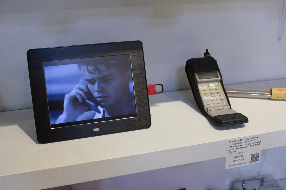 A large Motorola cell phone from 1989 next to a digital photo frame playing the original commercial for that phone