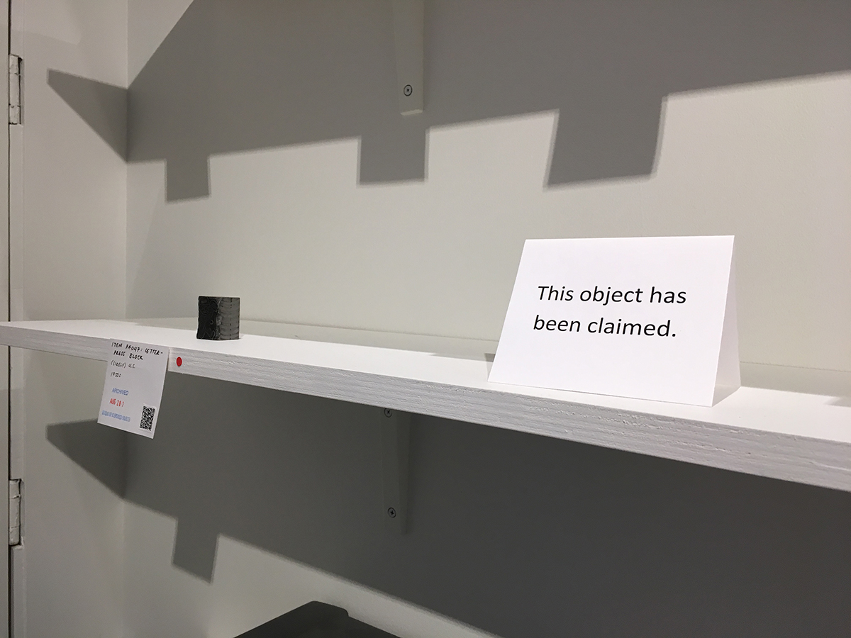 a red dot sticker next to an object on the shelf, next to an empty space with a sign saying, This object has been claimed