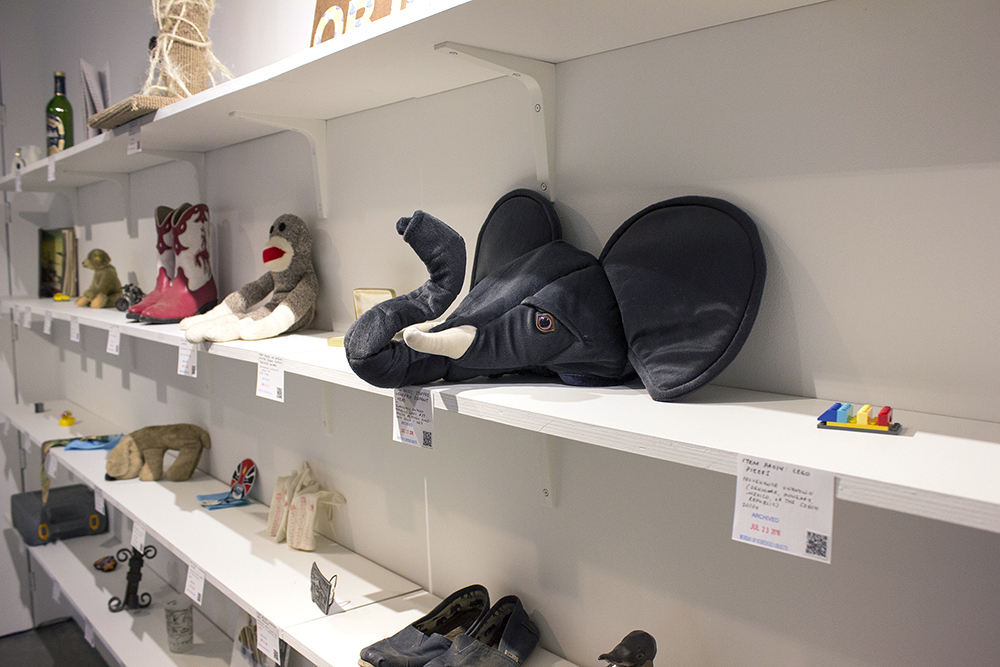 four shelves of objects, including an elephant-shaped hat, sock monkey, cowboy boots, an d a cat scratching post