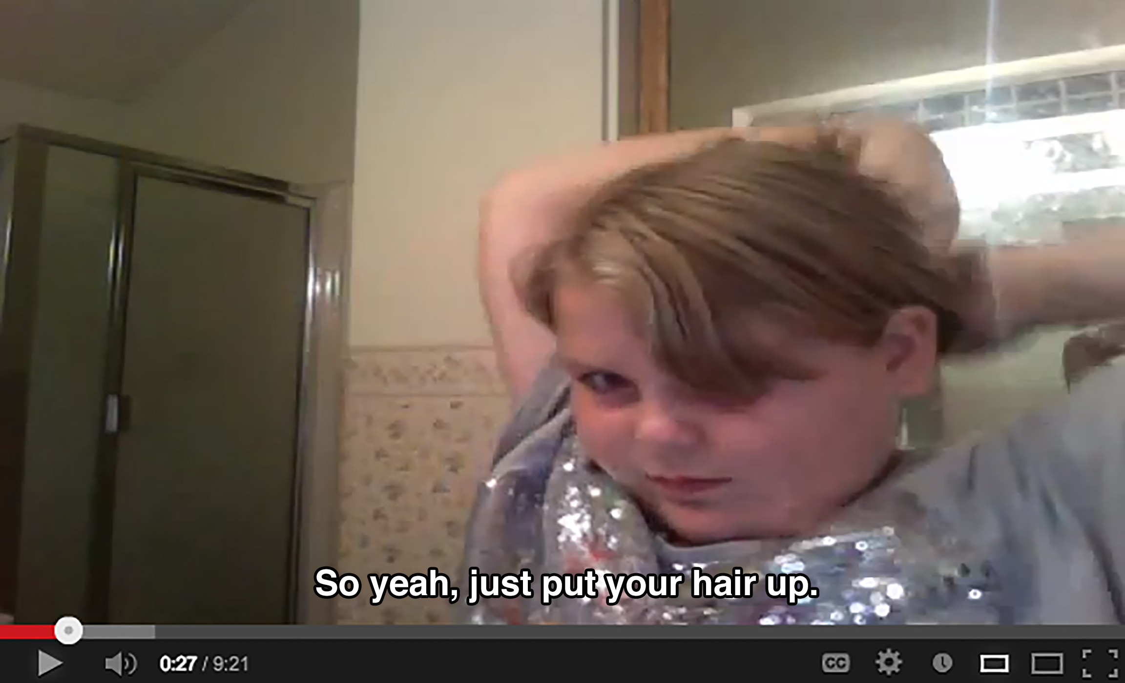A young girl in a bathroom wrangles her hair while saying: So yeah, just put your hair up.