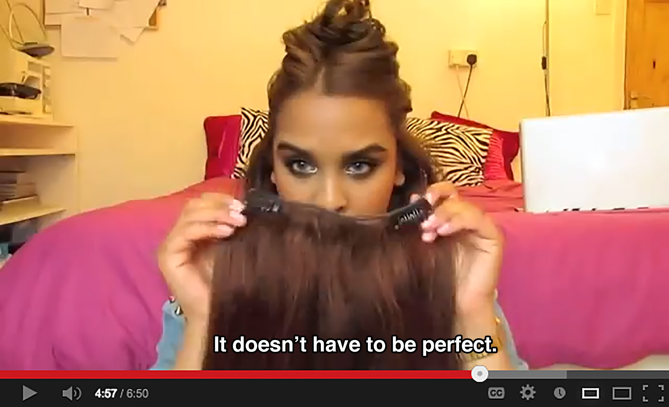 A young woman in her bedroom holds hair extensions and says: It doesn't have to be perfect.