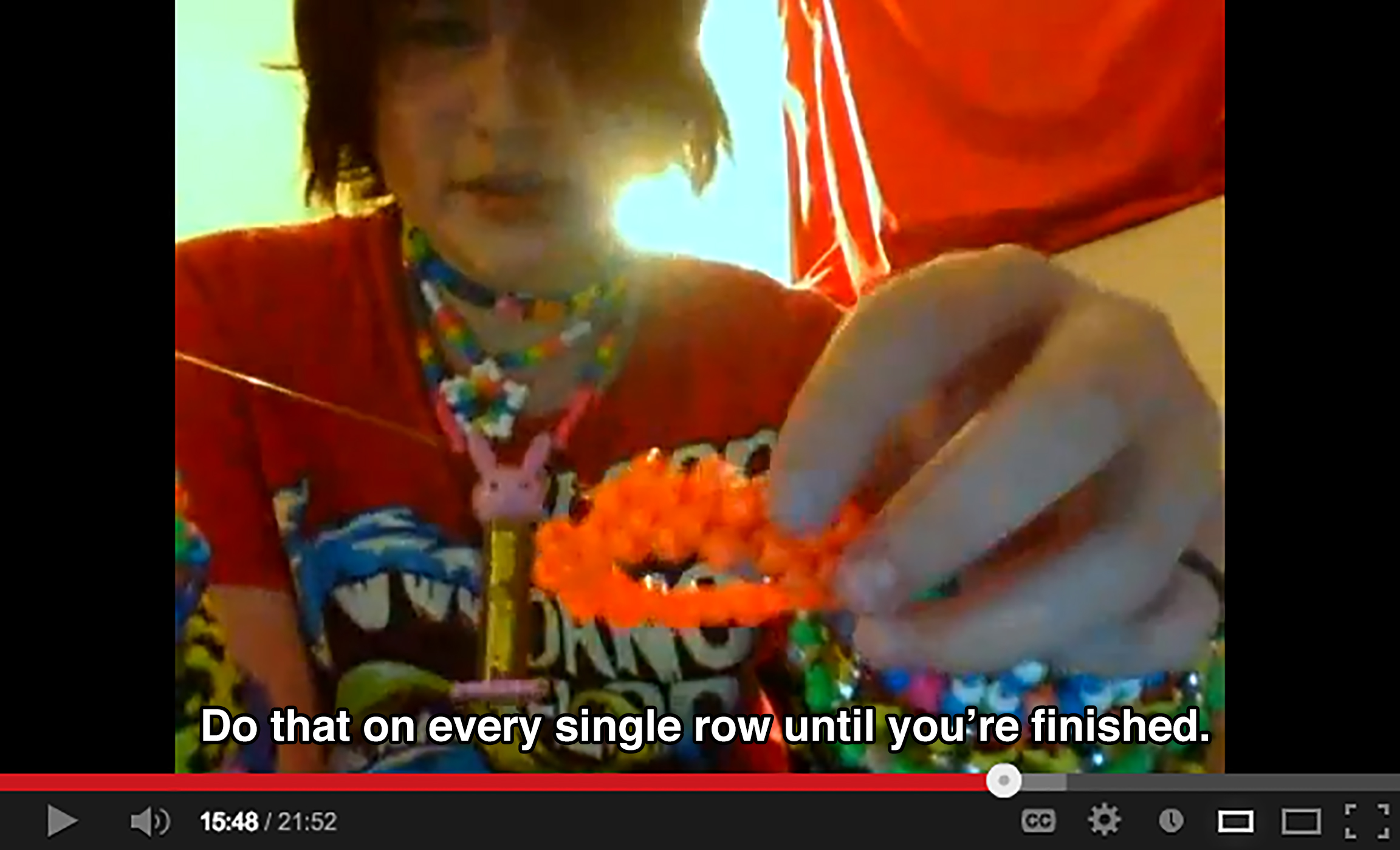 A teenager wearing many of their bead projects holds up a bracelet made of orange beads to the camera and says: Do that on every single row until you're finished.